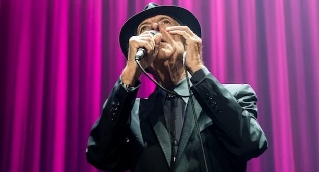 The late, great Leonard Cohen, sings live in trademark hat in front of purple curtains