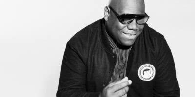 Carl Cox snapping his fingers, wearing dark sunglasses and a black bomber jacket