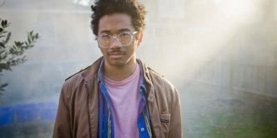 Toro Y Moi standing in a hazy suburban landscape