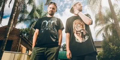 Hermitude standing with black t-shirts infront of palm trees in Manly