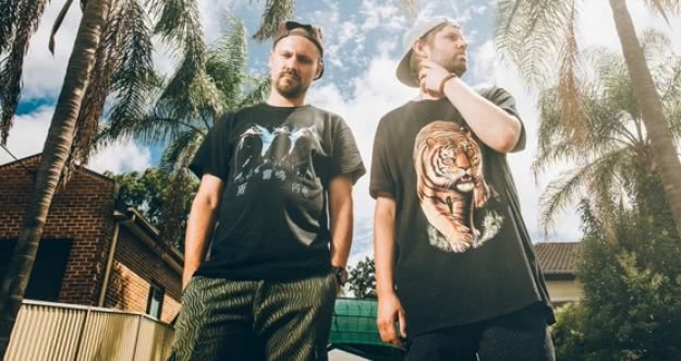 Hermitude standing with black t-shirts infront of palm trees in Manly