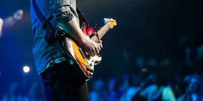 A guitarist performs onstage in front of a crowd