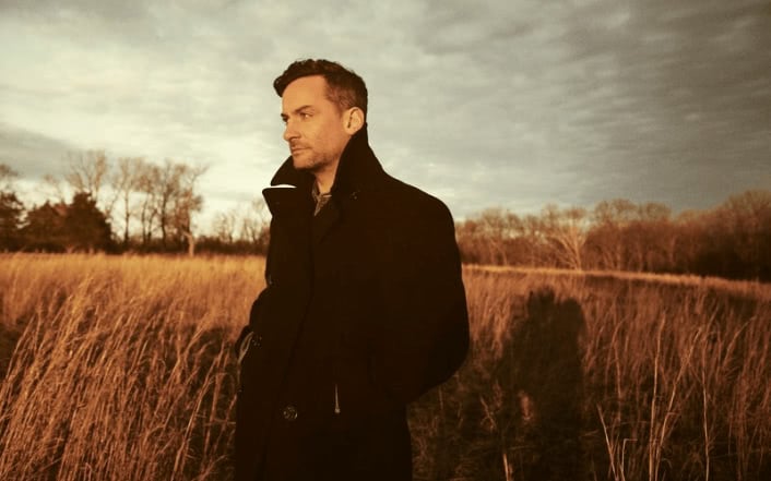 Electronic musician Bonobo standing alone in a field