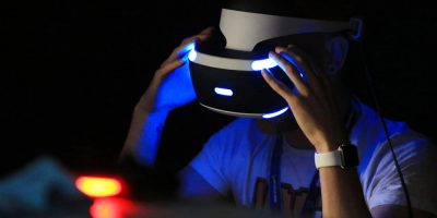 A man weraing a PlayStation VR headset in the dark