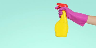 Someone cleaning with a spray bottle while wearing gloves