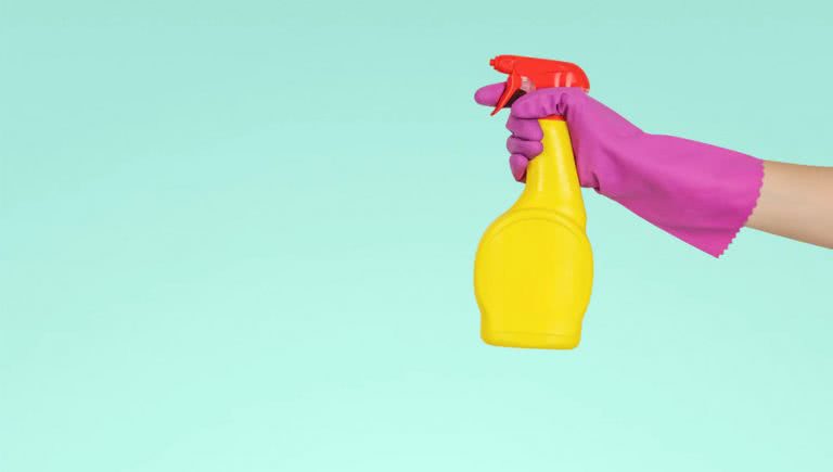 Someone cleaning with a spray bottle while wearing gloves