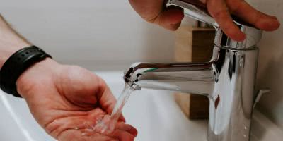 Image of someone turning on a tap to wash their hands.