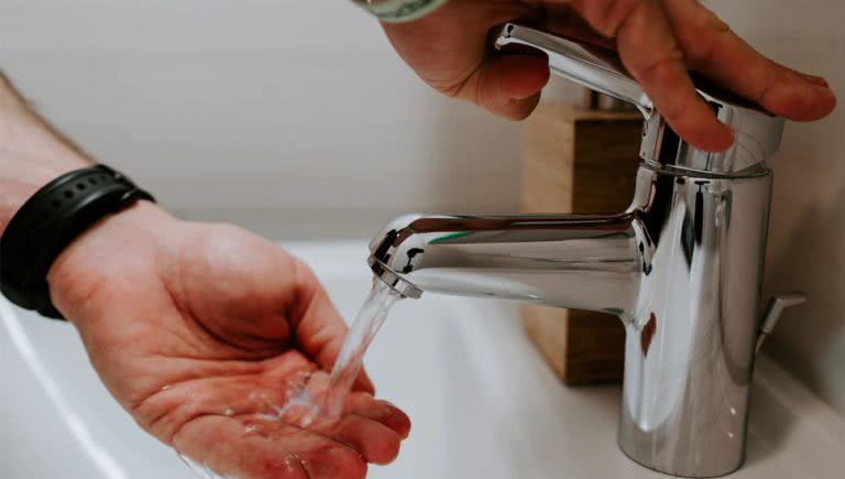 Image of someone turning on a tap to wash their hands.