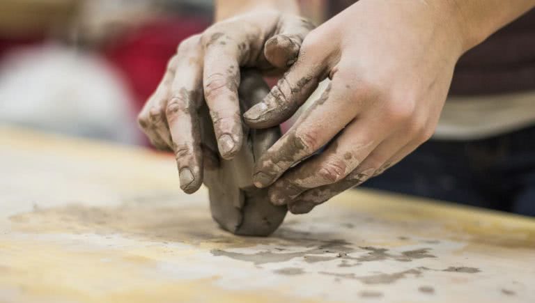 Someone moulding clay into pottery