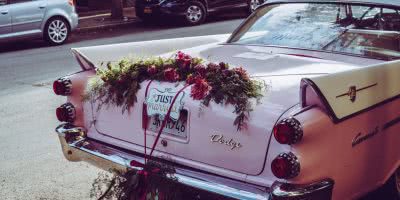 Photo of a pink wedding car with a 'just married' sign on it.