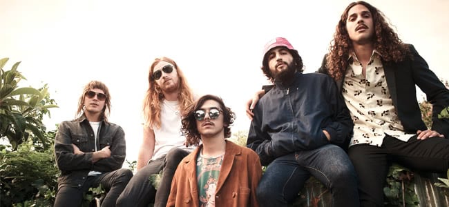 Sticky Finger band members sitting on a wall looking down at the camera