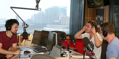 three men sitting in a studio talking into microphones