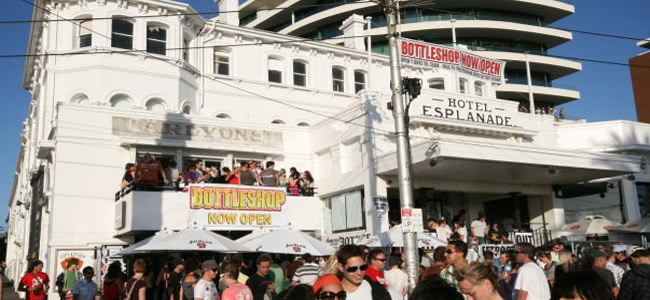 Crowd standing in front of white building called Hotel Esplanade