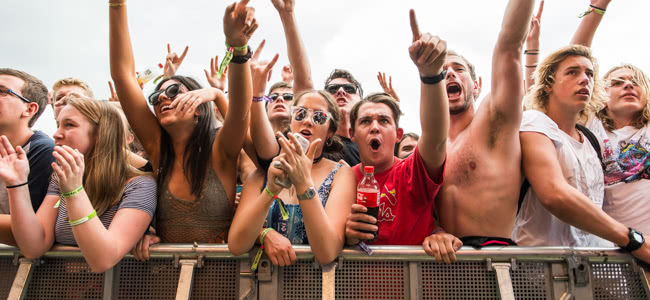 People standing in a crowd against a barricade with their hands in the air