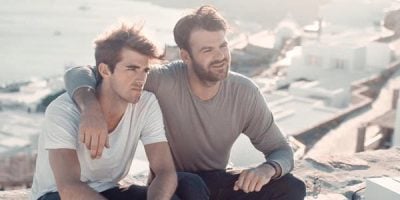 The Chainsmokers band members sitting on a ledge wearing a grey and white top