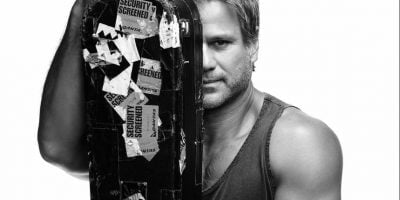 Jon Stevens holding a guitar case in front of his face