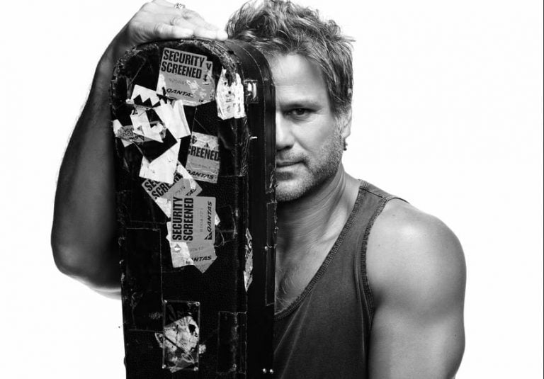 Jon Stevens holding a guitar case in front of his face