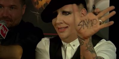 Marilyn Manson with black and white shite holding his hand out