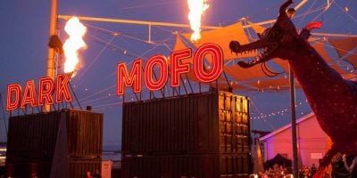 Dark Mofo sing lit up standing on containers with fire and a dragon statue