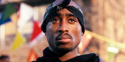 Close up of Tupac wearing a black jumper and a black bandana tied around his head