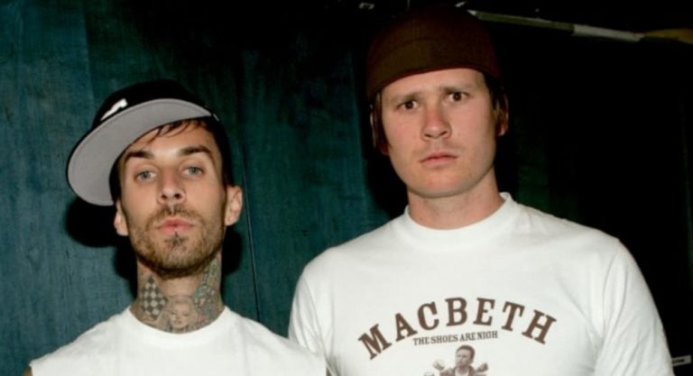 Tom DeLonge and Travis Barker looking at camera wearing white tshirts and black caps