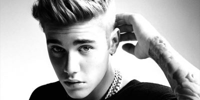 Black and white image of Justin Bieber with his hand behind his head.