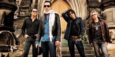 Four Band members from Stone Temple Pilots standing infant of an old building looking at the camera