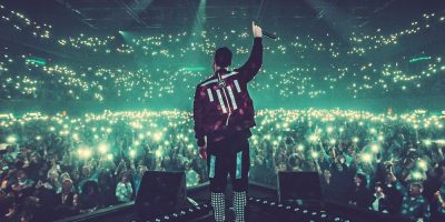 A DJ standing before a large crowd