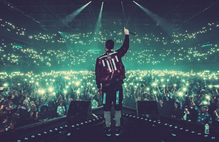 A DJ standing before a large crowd