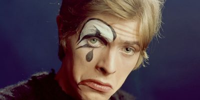 A young David Bowie wearing sad clown makeup