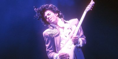 Prince plays his guitar onstage