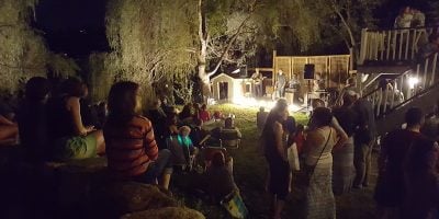 An example of secret gigs, with a concert being performed in a backyard at dusk
