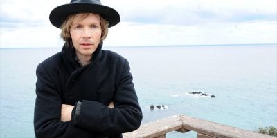 Legendary alt-rocker Beck, standing with the ocean in the background