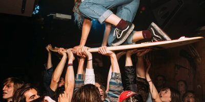 A member of Stork riding a surf board on a mosh pit