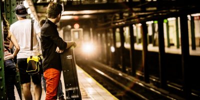 A man with a guitar case waits for a train in the New York Subway