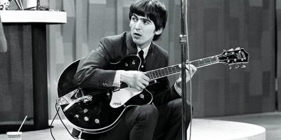 Late member of The Beatles, George Harrison, sitting with his guitar