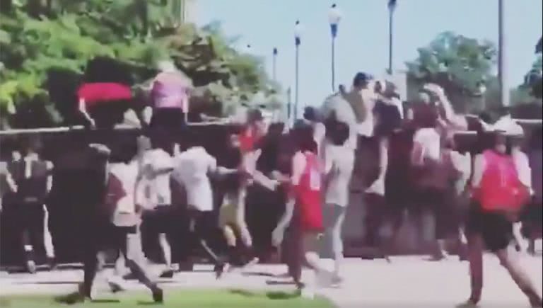 Image of people attempting to jump the fence to enter Lollapalooza