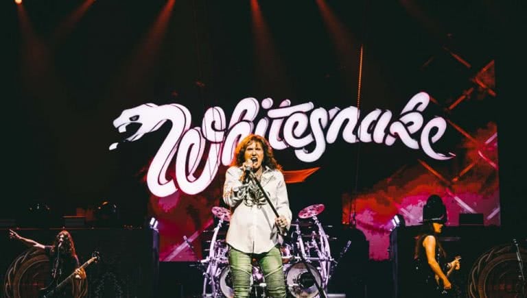 Whitesnake performing in front of their logo