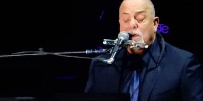 Iconic singer-songwriter Billy Joel playing piano and singing.