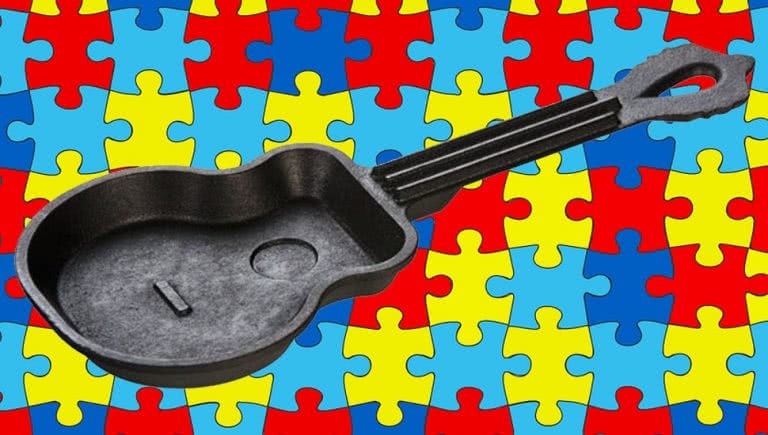 Cast iron guitar skillet in front of an autism puzzle background.