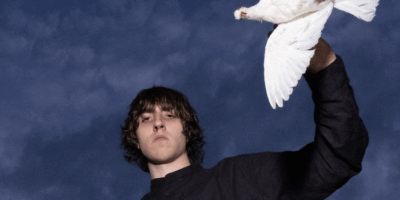 Cameron Winter posing for the camera with a bird on his arm