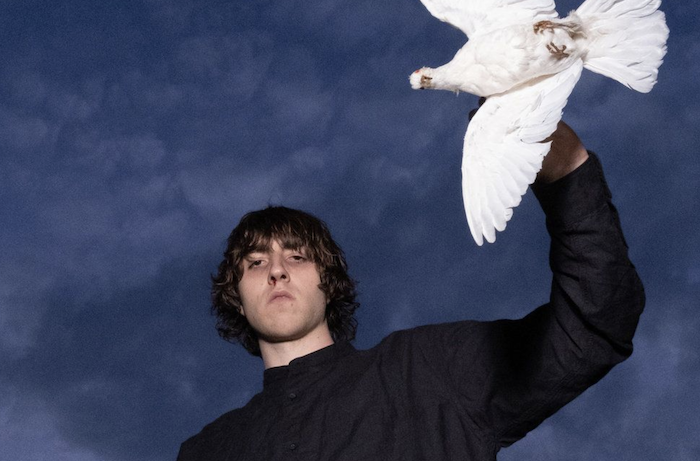 Cameron Winter posing for the camera with a bird on his arm