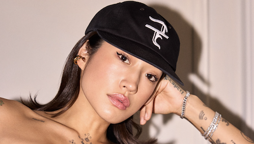 Peggy gou in a hat posing for the camera, leaning on her arm