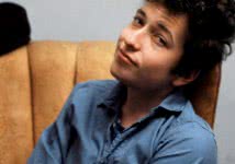 Man sitting on a lounge wearing a blue shirt smiling at the camera